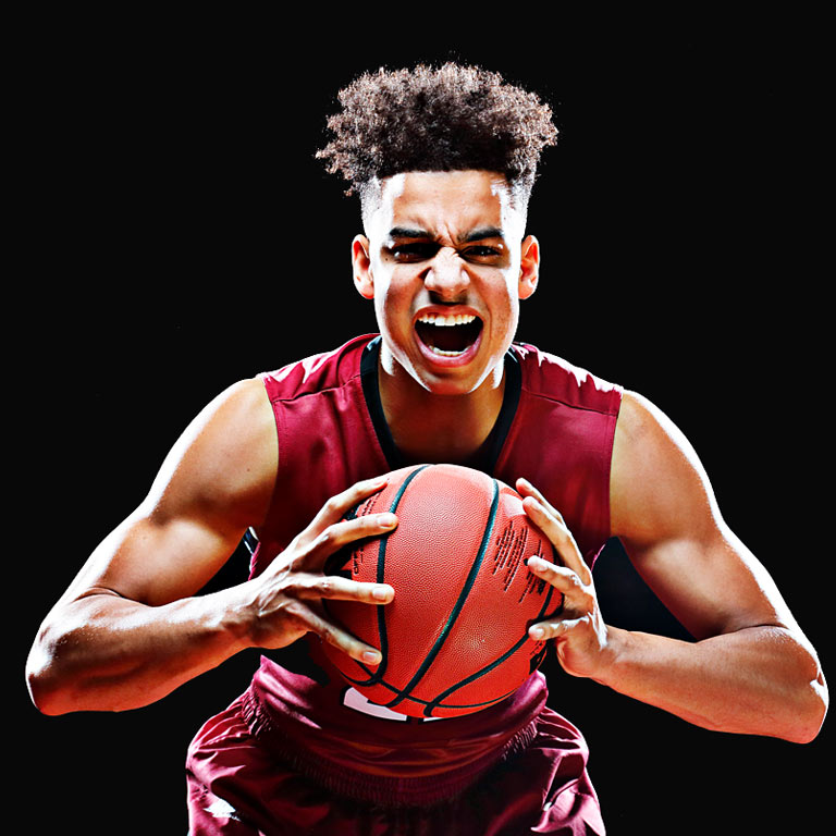 A male IUPUI basketball player holds a basketball and roars as part of the IUPUI Roar campaign